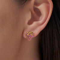 Gold and purple strawberry-shaped earring worn on an ear
