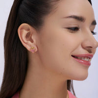 Close-up of a woman wearing pink heart-shaped earrings against a white background