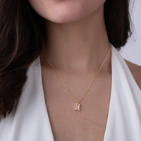 Gold vermeil necklace with a pink gemstone pendant worn by a person in a white outfit.