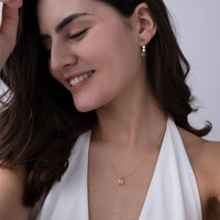 Woman wearing a gold vermeil necklace and earrings against a neutral background